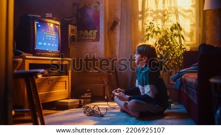 Young Boy Playing Eighties Eight Bit Arcade Space Shooter Video Game on a Console at Home in His Vintage Room with Old-School Interior. Child Successfully Wins the Level. Nostalgic Retro Childhood.