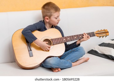 Young Boy Playing Guitar On Sofa