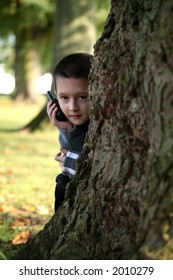 Young boy playing hide and seek holding a mobile phone