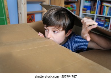 Young Boy Is Playing Hide And Seek Inside A Cardboard Box In His Room