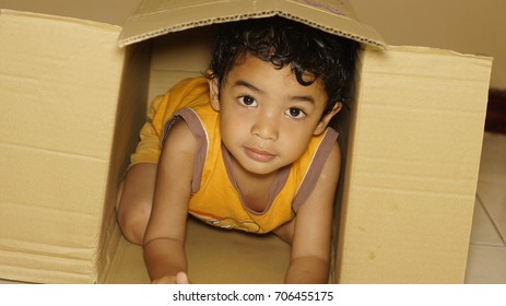 Young boy playing hide and seek in a box
