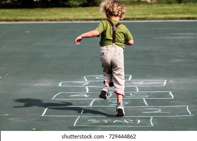 A Young Boy Playing Hop Scotch At The Playground 