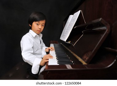 Young Boy Playing Piano (isolated On Black Background)