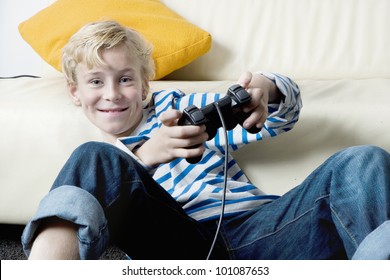 Young Boy Playing With A Playstation At Home.