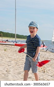 Young Boy Playing With Sand And On Shovel Beach