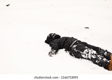 Young Boy Playing In Snowy Winter Wonderland Wearing Snowsuit