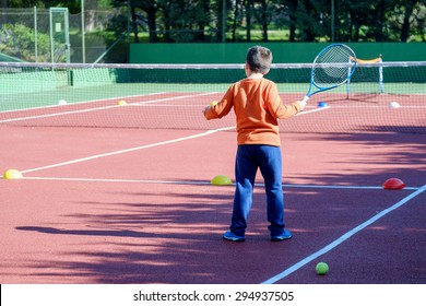 Young boy playing tennis on a court