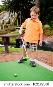 Young Boy Plays Mini Golf On Putt Putt Course