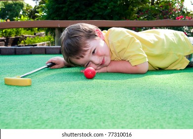 Young Boy Plays Mini Golf On Putt Putt Course.