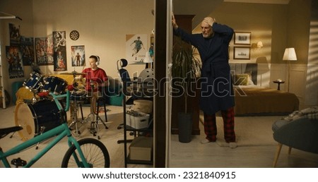 Young boy plays on drum kit at home. Elderly man irritated by noisy neighbor, screams, knocks on the wall. Low level of sound insulation. Apartments separated by wall. Neighbourhood concept.