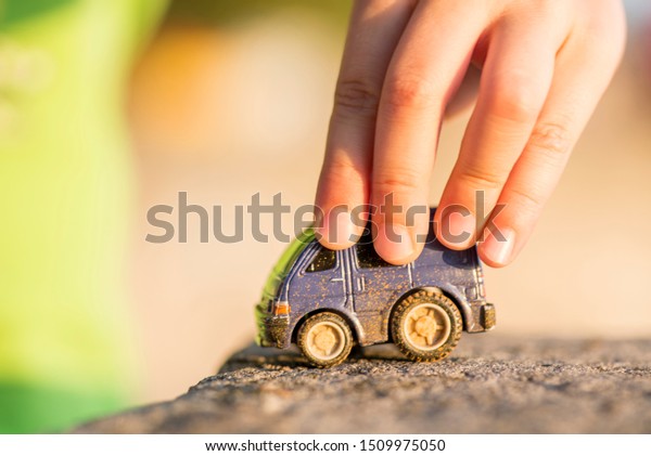 Young boy plays with toy car. Little boy playing\
with car toy on sunset.