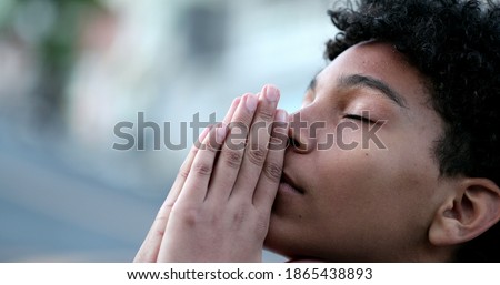Young boy praying to God. Religious Mixed race child looking at sky with HOPE and FAITH
