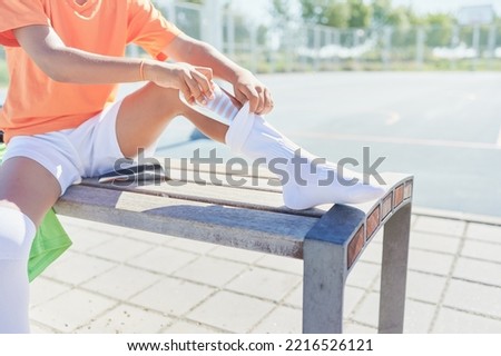 Young boy prepares his shin guards before playing football in a training field. Football match concept.