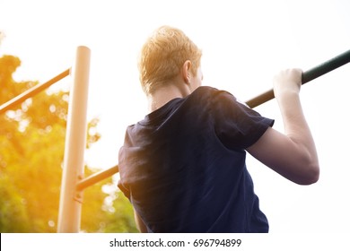 young boy pulled on the bar in the Park, the view from the back closeup. concept sports.