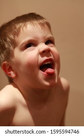 Young boy pulling silly face, sticking out tongue