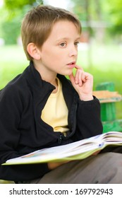 Young Boy Reading A Book At The Park