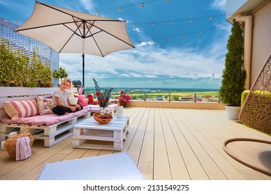 young boy relaxing on furnished rooftop patio at warm sunny day