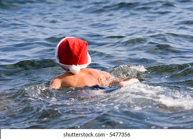 Young Boy In Santa Claus Red Hat Swimming In The Sea