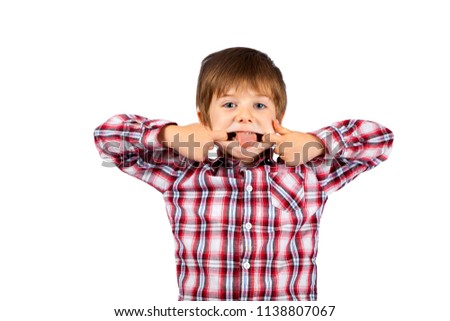 A young boy, with shaggy hair, makes a funny face with his tongue sticking out.  He is wearing a plaid shirt and is on a white background, isolated, with a clipping path.  Copy space.