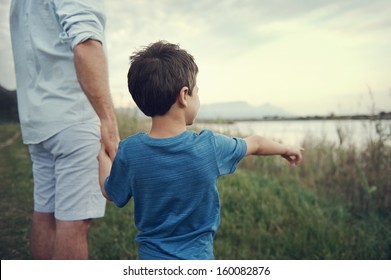 young boy showing his father something while holding hands in the park