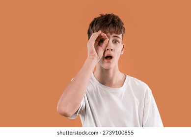 Young boy shows surprise while making a gesture with his hand in orange background