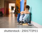 Young boy sitting alone with sad feeling at school. Bullying, discrimination and racism concept with copy space.