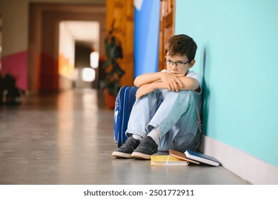 Young boy sitting alone with sad feeling at school. Bullying, discrimination and racism concept with copy space. - Powered by Shutterstock