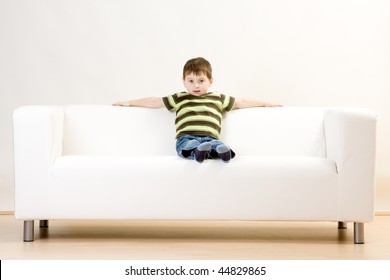 A Young Boy Sitting On A White Couch.