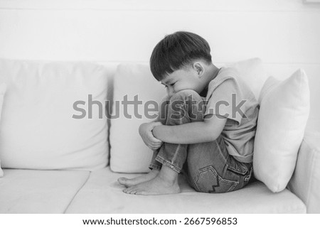 Young boy sitting with thoughtful expression, child feeling emotional sadness and sorrow, melancholic mood, childhood emotions, feeling lonely, introspection and reflection, grief and solitude
