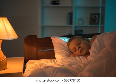 The Young Boy Sleeping On The Bed At Night