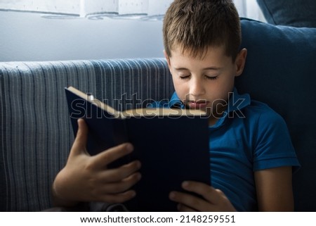 Young boy sleeping while reading a book in bed