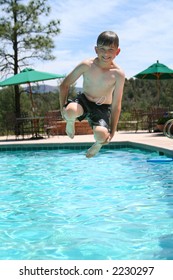 Young boy smiling and jumping into a swimming pool