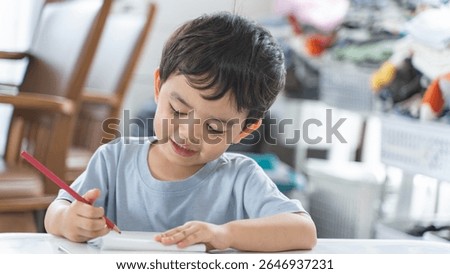 A young boy smiling while doing his homework at home, showing focus and enjoyment during a learning activity. Perfect representation of joyful early education.