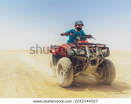 young boy speeding on a quad bike in the desert 