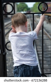 Young boy standing at back of train looking down at track
