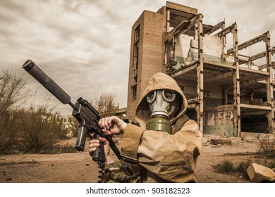 young boy stands with a gun in his hand. laser tag game. boy in a gas mask. boy in a protective cloak and hood. child standing near the destroyed building. a child soldier. young boy soldiers.