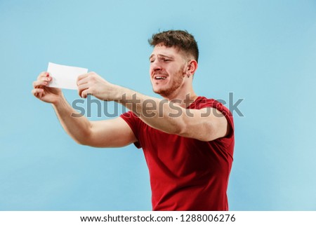 Young boy with a surprised happy expression bet slip on blue studio background. Human facial emotions and betting concept. Trendy colors