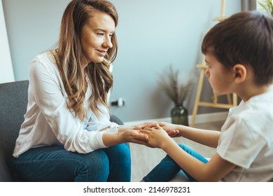 Young Boy Talking With Counselor At Home. Female Psychologist Working With Little Boy In Office. Young Female School Psychologist Having Serious Conversation With Smart Little Boy