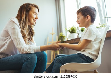 Young Boy Talking With Counselor At Home. Female Psychologist Working With Little Boy In Office. Young Female School Psychologist Having Serious Conversation With Smart Little Boy