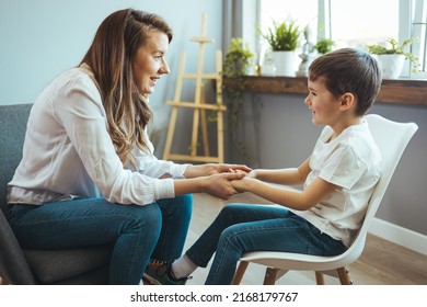 Young Boy Talking With Counselor At Home. Female Psychologist Working With Little Boy In Office. Young Female School Psychologist Having Serious Conversation With Smart Little Boy