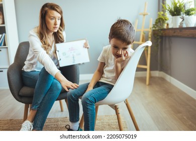 Young Boy Talking With Counselor At Home. Young Female School Psychologist Having Serious Conversation With Smart Little Boy At Office. Five Years Old Boy At The Psychotherapy Session.