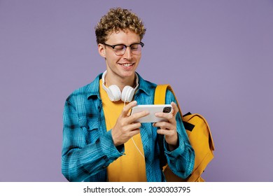 Young boy teen student in casual clothes backpack headphones glasses play racing app on mobile cell phone gadget smartphone isolated on violet background studio Education in university college concept - Powered by Shutterstock