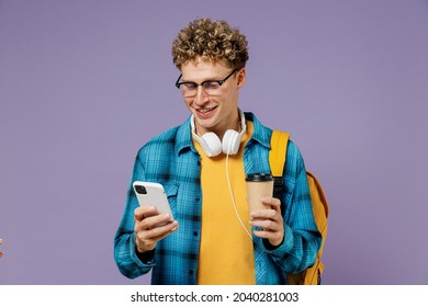 Young Boy Teen Student In Casual Clothes Backpack Headphones Glasses Hold Takeaway Delivery Cup Coffee Use Mobile Phone Isolated On Violet Background Studio Education In University College Concept.