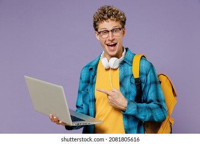 Young Boy Teen Student In Casual Clothes Backpack Headphones Glasses Hold Use Work Point Finger On Laptop Pc Computer Isolated On Plain Violet Background Studio Education In University College Concept