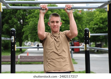 Young boy, teenager doing outdoor sport, workout on horizontal bar, healthy sport life - Powered by Shutterstock