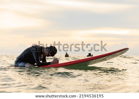 Young boy teenager surfboarder bows his head in exhaustion, tired, and disappointment during learning and practicing surfing. Concept for failing training, pause, and trying to fight again. ストックフォト © 