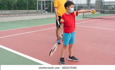 A Young Boy With The Tennis Coach.The Kid Is Learning With The Instructor.A Parent Teaches A Son Playing Techniques. Kids Tennis On The Big Court. Tennis School Or Club. 