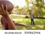 Young boy throwing American football to his dad in park