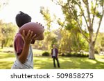 Young boy throwing ball to dad in park, focus on foreground