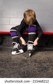 A Young Boy Ties His Hockey Skates in Rink Dressing Room